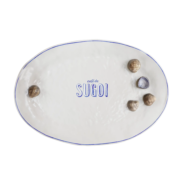 Håndlavet hvid tallerken fra Sugoi Studio med blå Café de Sugoi-logo og muslingedetaljer – legesyg og unik til moderne borddækning.